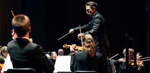 Cornelius Meister steht am Dirigentenpult und dirigiert das Orchester.